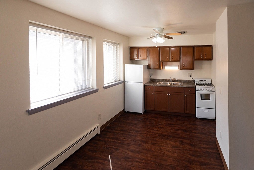 a kitchen with white appliances and a ceiling fan